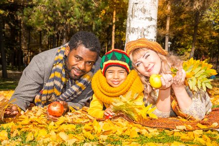 Happy family in autumn park. African American family: black father, mom and child boy on nature in fall.の写真素材