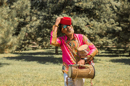 Handsome African man in a national costume plays an ethnic drum, djembe.の写真素材