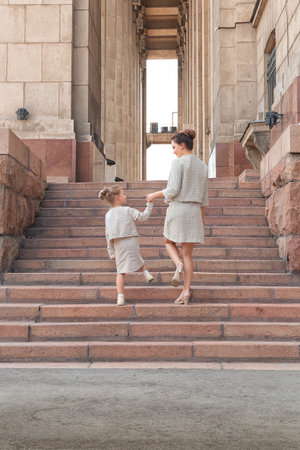 Happy smiling mom with a daughter child on a sunny summer day. Mother and girl kid walking around the city in the arch. Happy familyの写真素材