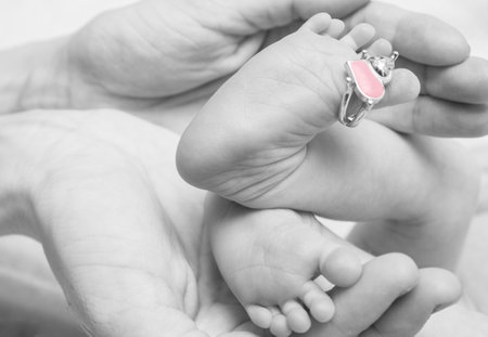 Parent holding in the hands feet of newborn baby. Closeup photoの写真素材