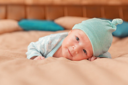 Portrait of a cute 3-month-old baby, a newborn boy lying in a bad. Newborn child relaxing in...