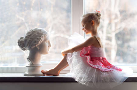 Girl ballerina in a tutu by the windowの写真素材