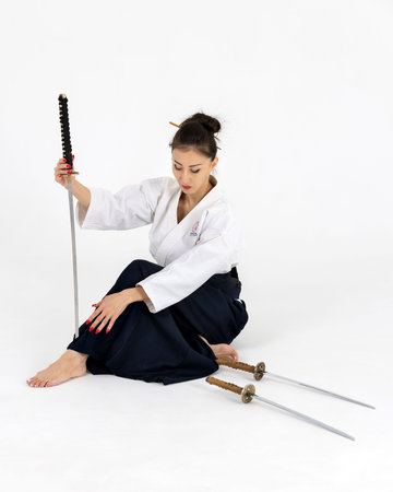 Aikido master woman in traditional samurai hakama kimono with black belt with sword, katana on white background. Healthy lifestyle and sports concept.の写真素材