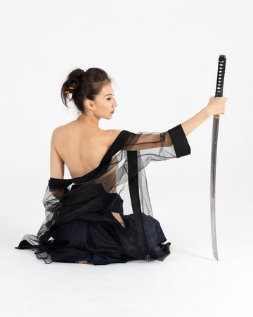Aikido master woman in traditional samurai hakama kimono with black belt with sword, katana on white...