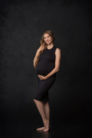 Pregnant woman on black background with big tummy, waiting for baby. Pregnancy, motherhood conceptの写真素材