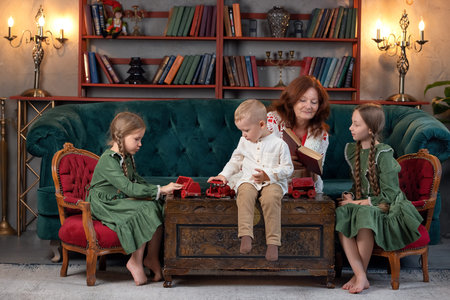Happy grandma and grandchildren reading book together and having fun at homeの写真素材