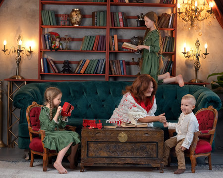 Happy grandma and grandchildren reading book together and having fun at homeの写真素材