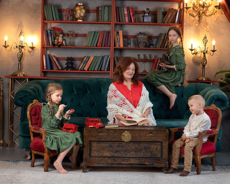 Happy grandma and grandchildren reading book together and having fun at homeの写真素材