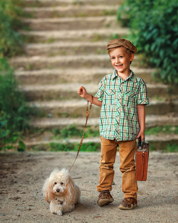 A boy kid with a poodle dog walks at street. Happy child in summer with petの写真素材