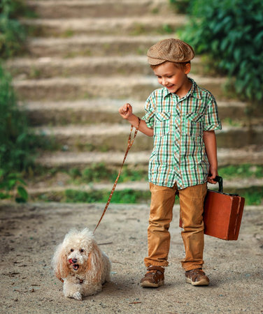 A boy kid with a poodle dog walks at street. Happy child in summer with petの写真素材