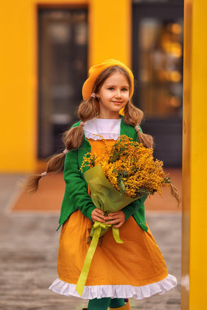Beautiful girl kid in beret with spring yellow mimosa flowers bouquet at city street. Portrait of pretty child with long hair in park outdoors.の写真素材