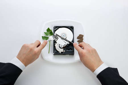 hard drive is on the dining plate with seasoning and herbs. man's hands cut drive a knife and forkの写真素材