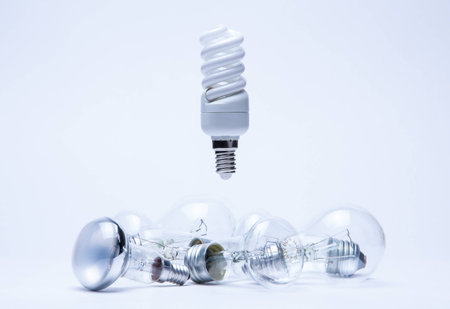 energy saving light hanging over incandescent lamps on white
