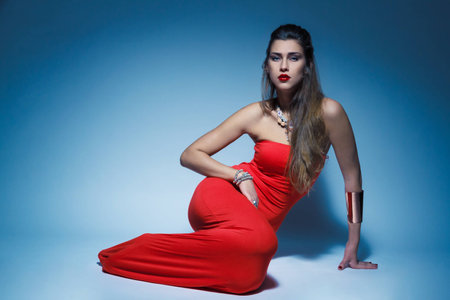 Young glamour woman in red dress long hair in studioの写真素材