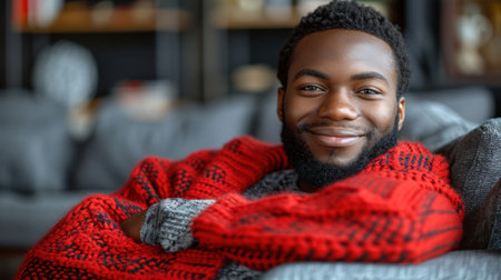A man in a red sweater sits on a couch.の素材