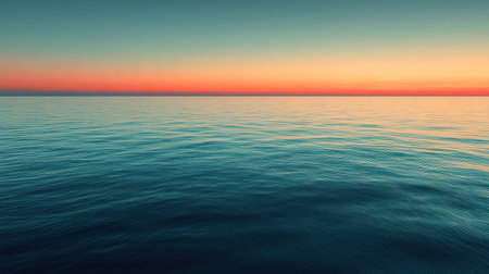 Soft waves gently lap at the surface of the ocean, reflecting vibrant colors as the sun sets below the horizon.の素材
