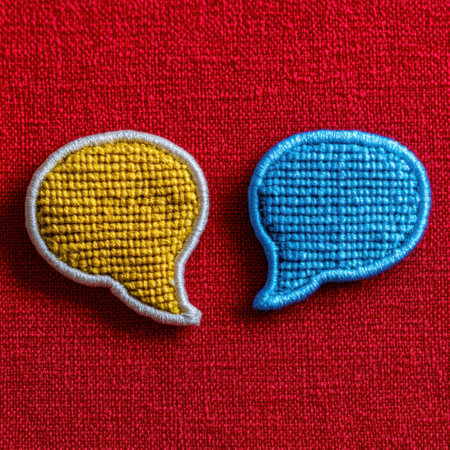 Two embroidered speech bubble patches in yellow and blue are positioned against a vibrant red background.の素材