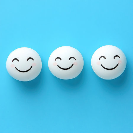 Three round white balls with smiling faces arranged in a row against a bright blue backdrop create a joyful ambiance.の素材
