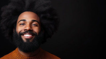 A joyful man displays a bright smile, showcasing his curly hair and beard while dressed in an orange sweater.の素材