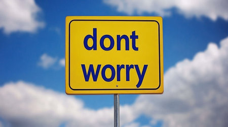 A cheerful yellow sign promotes a carefree mindset with the phrase don't worry against a picturesque sky.の素材