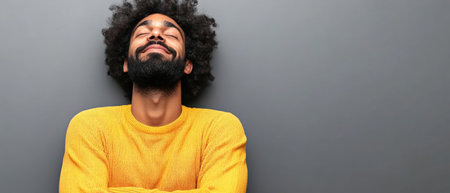 A man wearing a bright yellow sweater expresses contentment with a serene smile, enjoying a peaceful moment.の素材