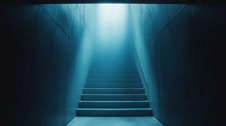 A staircase leads upward, softly illuminated by light streaming from above in a dark setting.の素材