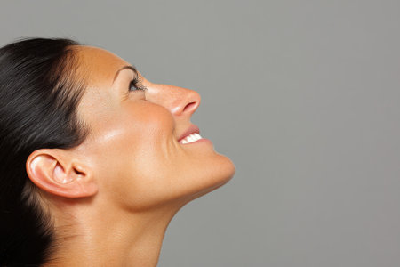 A woman is smiling and gazing upwards showcasing a sense of optimism and joy.の素材