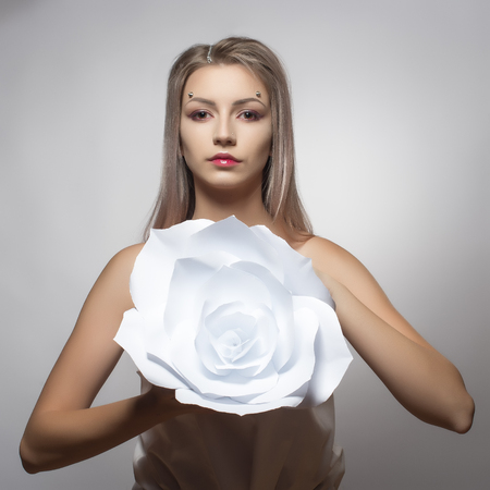 Girl holding a paper flower in her handの写真素材