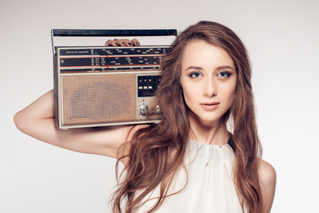Sexy girl in white dress is holding a retro radioの写真素材