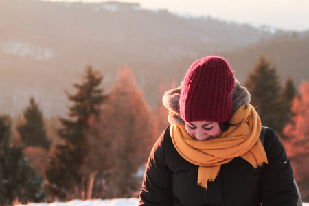 A girl is watching the display of her camera, after she took a picture of a snowy landscapeの写真素材