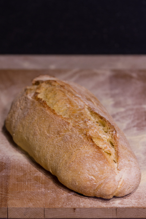 A fresh-baked bread on a cutting board, representing Italian food, Homemade food, Warmth, Tradition, etcの写真素材