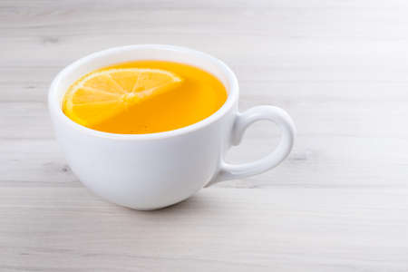 Cup of lemon tea with ginger. On a white wooden table.の写真素材