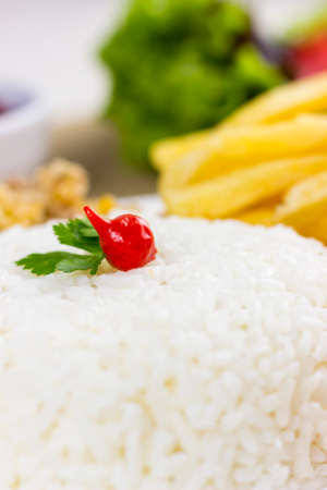 Rice with chicken filet and french fries on a white plate with a raw cotton dish towel. Selective focus.の写真素材