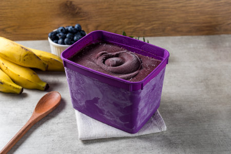 Brazilian frozen aÃ§ai berry ice cream purple pot box. with fruits on wooden background. Summer menu front view.の写真素材