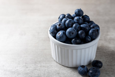 Lot of fresh delicious blueberries on a white pot over a wooden table.の写真素材