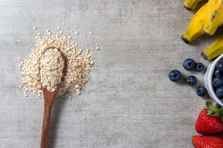Background with a spoon full of oats and some fresh healthy fruits on a wooden table. Bananas, Blueberries and strawberries. top view. Copy space.の写真素材
