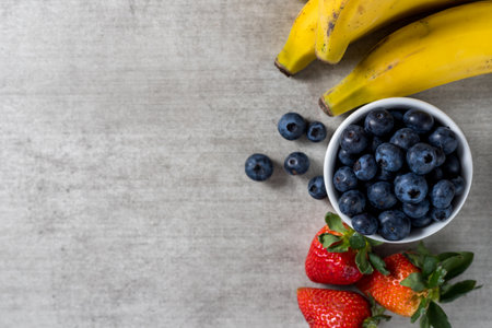 Background with fresh healthy fruits on a wooden table. Bananas, Blueberries and strawberries. top view. Copy space.の写真素材