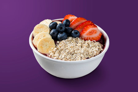Brazilian frozen aÃ§ai berry ice cream bowl with strawberries, bananas, blueberry and granola. isolated on purple background. Summer menu front view.の写真素材