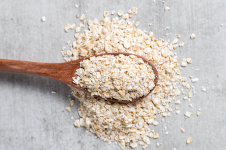 wooden spoon with oatmeal flakes on a gray wood backrgound. top view. copy space.の写真素材