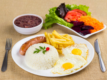 Typical Brazilian food, executive dish, food menu. Sausage, rice, beans, potato and crumbs with accompaniments.の写真素材