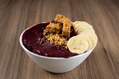 White Bowl of Brazilian Frozen AÃ§ai Berry With PaÃ§oca and Banana. on a wooden desk..の写真素材