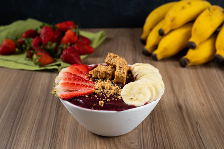 White Bowl of Brazilian Frozen AÃ§ai Berry With PaÃ§oca, Strawberry and Banana. on a wooden desk and fruits on background.の写真素材