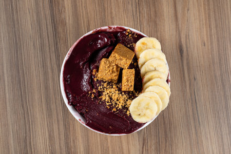 White Bowl of Brazilian Frozen AÃ§ai Berry With PaÃ§oca and Banana. on a wooden desk. Top view.の写真素材