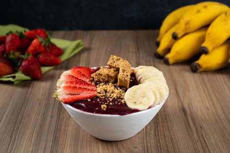White Bowl of Brazilian Frozen AÃ§ai Berry With PaÃ§oca, Strawberry and Banana. on a wooden desk and fruits on background.の写真素材