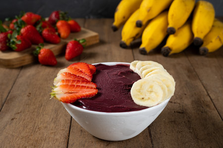 White Bowl of Brazilian Frozen AÃ§ai Berry with Banana and Strawberry. on a wooden desk. Fruits on background.の写真素材