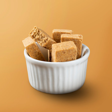 A bowl full of Brazilian Peanut Sweet called PaÃ§oca isolated on orange background.の写真素材