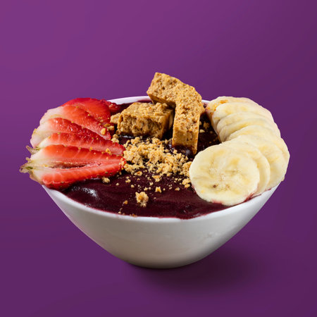 Brazilian AÃ§ai Bowl with PaÃ§oca, Banana and Strawberry isolated on purple background.の写真素材