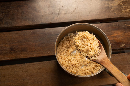 brown rice at the cooker on a wooden deskの写真素材
