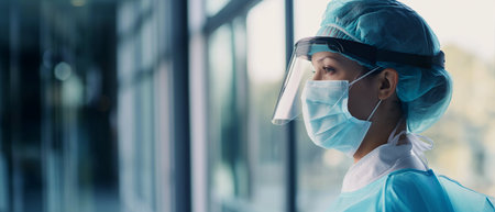 Portrait of female surgeon looking at camera while standing in hospital corridorの素材