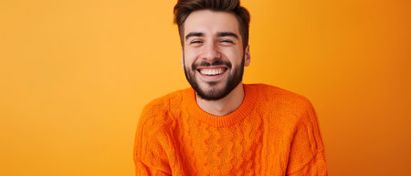 smiling young man in orange sweater looking at camera isolated on yellowの素材